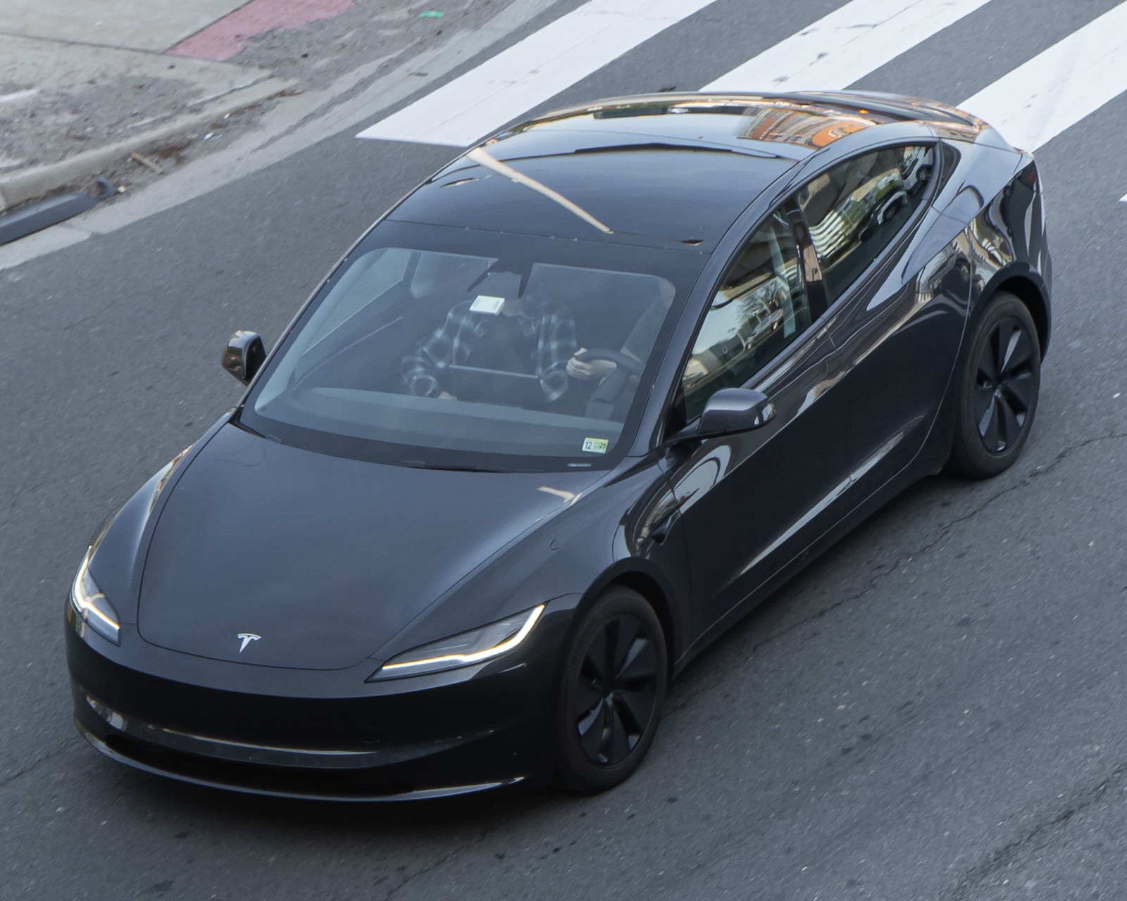 도로를 주행하는 Tesla Model 3 Highland의 전면과 측면. 2025년 촬영 사진.